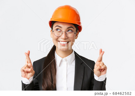 Close-up of hopeful optimistic asian female engineer, architect having faith in project, wearing safety helmet and business suit awaiting good results, cross fingers good luck, white background Close-up of hopeful optimistic asian female engineer, architect having faith in project, wearing safety helmet and business suit awaiting good results, cross fingers good luck, white background 68462502