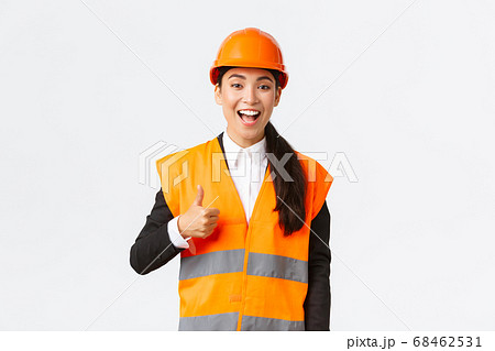 Supportive and pleased happy asian female chief engineer in safety helmet showing thumbs-up in approval, satisfied with construction work. Industrial woman in reflecive jacket inspect area Supportive and pleased happy asian female chief engineer in safety helmet showing thumbs-up in approval, satisfied with construction work. Industrial woman in reflecive jacket inspect area 68462531