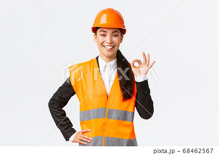 Confident professional asian female architect in safety helmet assure quality and work in time, showing okay gesture and smiling determined, standing assertive, ensure and guarantee something Confident professional asian female architect in safety helmet assure quality and work in time, showing okay gesture and smiling determined, standing assertive, ensure and guarantee something 68462567