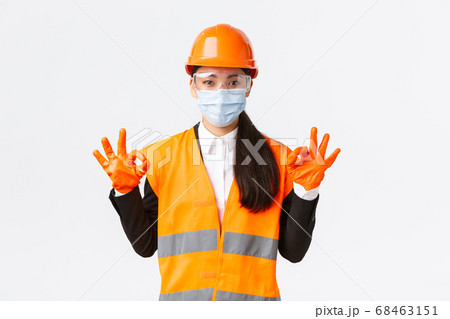 Covid-19 safety protocol at enterpise, construction and preventing virus concept. Satisfied asian female engineer, industrial woman face mask showing okay gesture, well done, praising good work Covid-19 safety protocol at enterpise, construction and preventing virus concept. Satisfied asian female engineer, industrial woman face mask showing okay gesture, well done, praising good work 68463151