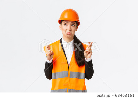 Sad nervous and unconfident asian female construction manager in safety helmet, pouting and look in panic upper left corner, making wish, cross fingers good luck, pleading over white background Sad nervous and unconfident asian female construction manager in safety helmet, pouting and look in panic upper left corner, making wish, cross fingers good luck, pleading over white background 68463161