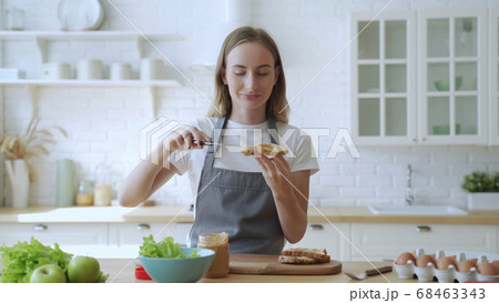 Happy smiling woman in the kitchen preparing a peanut butter sandwich 68463343