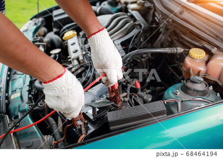 Mechanic hands charging old car with electricity trough jumper cables 68464194