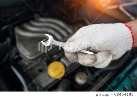Mechanic holding wrench with old car engine blur background 68464199