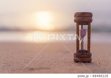 Small hourglass show time is flowing on sand beach 68466226