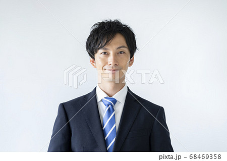 カメラ目線で微笑むスーツ姿の若い男性の写真素材