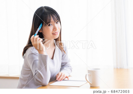 部屋でノートにメモを書く若い女性 部屋でノートにメモを書く若い女性 68472003