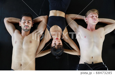 group of sporty caucasian woman and man in sport wear lying on fitness floor and resting group of sporty caucasian woman and man in sport wear lying on fitness floor and resting 68473285