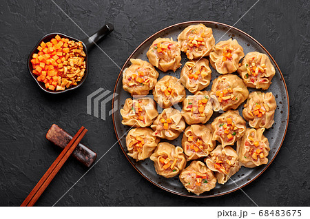 Shumai or Kanom Jeeb or Steamed Pork and Shrimp. Dumplings on a black plate on dark slate backdrop. Shumai or Kanom Jeeb or Steamed Pork and Shrimp. Dumplings on a black plate on dark slate backdrop. 68483675