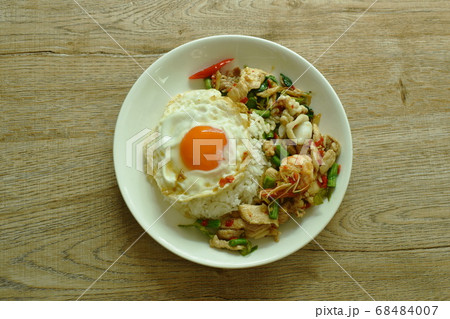 spicy fried seafood and meat chili and herb on rice topping egg in plate spicy fried seafood and meat chili and herb on rice topping egg in plate 68484007