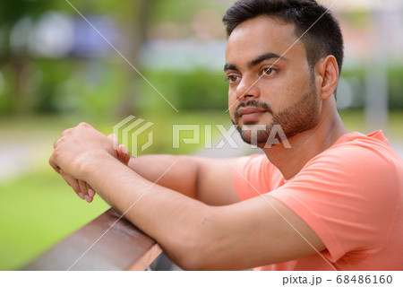 Young handsome bearded Indian man at the park Young handsome bearded Indian man at the park 68486160