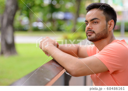 Young handsome bearded Indian man at the park 68486161