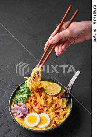 Ohn No Khao Swe in black bowl at dark slate tabl top. Myanmar Coconut Milk Noodle Soup Ohn No Khao Swe in black bowl at dark slate tabl top. Myanmar Coconut Milk Noodle Soup 68486683