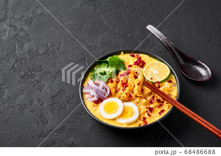 Ohn No Khao Swe in black bowl at dark slate tabl top. Myanmar Coconut Milk Noodle Soup 68486688