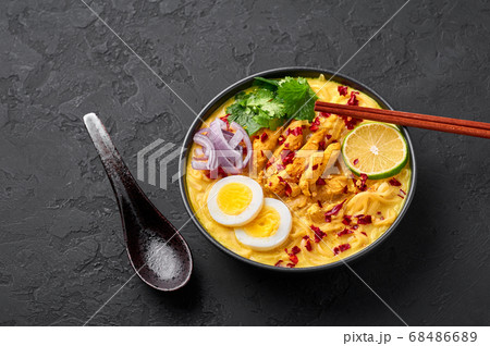 Ohn No Khao Swe in black bowl at dark slate tabl top. Myanmar Coconut Milk Noodle Soup Ohn No Khao Swe in black bowl at dark slate tabl top. Myanmar Coconut Milk Noodle Soup 68486689