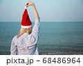 Girl in a red Christmas hat on the beach next to the sea. Holiday concept. 68486964