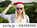Girl in a red Christmas hat next to the swimming pool with blue water. Holiday concept. 68486966