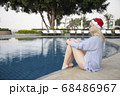 Girl in a red Christmas hat next to the swimming pool with blue water. Holiday concept. 68486967
