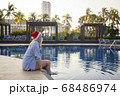 Girl in a red Christmas hat next to the swimming pool with blue water. Holiday concept. 68486974