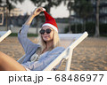 Girl in a red Christmas hat on the beach next to the sea. Holiday concept. 68486977