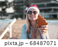 Girl in a red Christmas hat on the beach next to the sea. Holiday concept. 68487071