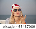 Girl in a red Christmas hat on the beach next to the sea. Holiday concept. 68487089