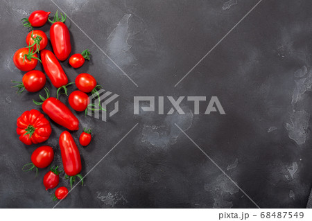 Red heirloom tomatoes on dark textured backdrop,  68487549