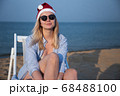 Girl in a red Christmas hat on the beach next to the sea. Holiday concept. 68488100