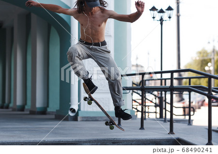 Young boy riding trick on skateboard in city 68490241