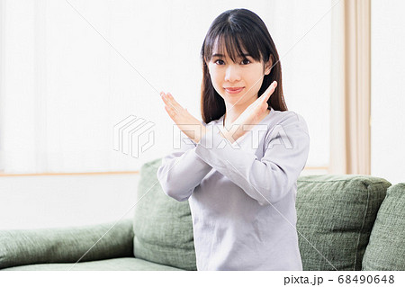 リビングのソファでNGのジェスチャーをする若い女性 リビングのソファでNGのジェスチャーをする若い女性 68490648
