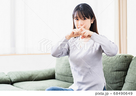 リビングのソファでNGのジェスチャーをする若い女性 リビングのソファでNGのジェスチャーをする若い女性 68490649