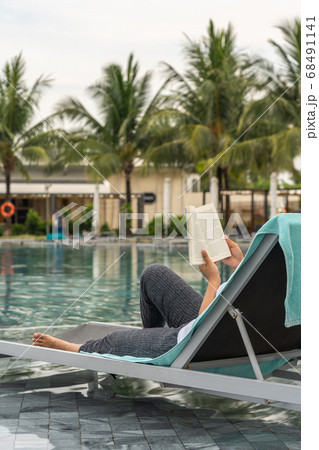 Woman hand holding book while reading at swimming pool Woman hand holding book while reading at swimming pool 68491141