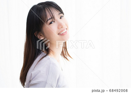 部屋の窓際に立つ若い女性 68492008