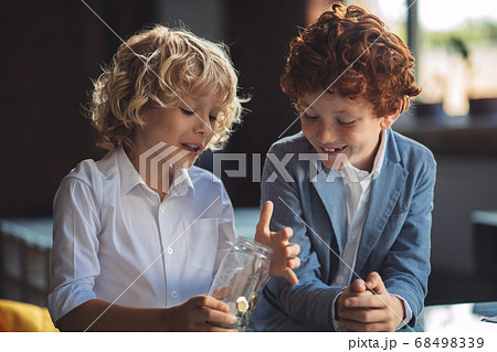 Two boys investigating the jar with coins 68498339