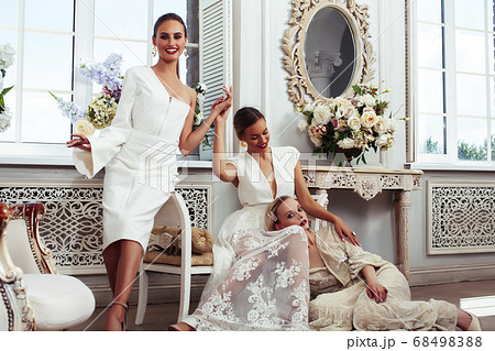 three young pretty lady in white lace fashion style dress posing in rich interior of royal hotel room, luxury lifestyle people concept, bride on wedding day three young pretty lady in white lace fashion style dress posing in rich interior of royal hotel room, luxury lifestyle people concept, bride on wedding day 68498388