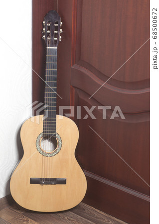 Acoustic guitar leaning against a wooden door Acoustic guitar leaning against a wooden door 68500672