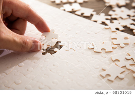 Hand putting the a last piece of white jigsaw Hand putting the a last piece of white jigsaw 68501019
