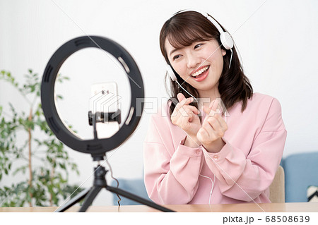 笑顔でライブ配信する若い女性のYouTuber 68508639