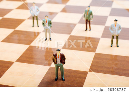 Miniature people standing on chessboard as Miniature people standing on chessboard as 68508787