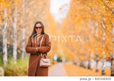 Fall concept - beautiful woman drinking coffee in autumn park under fall foliage Fall concept - beautiful woman drinking coffee in autumn park under fall foliage 68508900