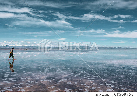 Man alone at endless salt flat Salar de Uyuni. Man silhouette and reflection in the Salar de Uyuni. Man alone at endless salt flat Salar de Uyuni. Man silhouette and reflection in the Salar de Uyuni. 68509756