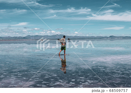 Man alone at endless salt flat Salar de Uyuni. Man silhouette and reflection in the Salar de Uyuni. Man alone at endless salt flat Salar de Uyuni. Man silhouette and reflection in the Salar de Uyuni. 68509757