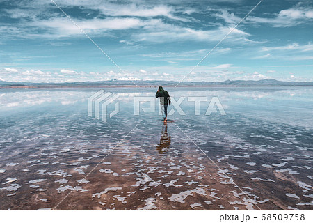 Man alone at endless salt flat Salar de Uyuni. Man silhouette and reflection in the Salar de Uyuni. Man alone at endless salt flat Salar de Uyuni. Man silhouette and reflection in the Salar de Uyuni. 68509758