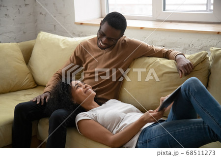 Positive smiling african couple in love resting on sofa together 68511273