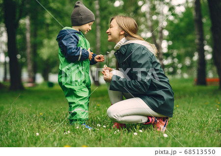 Funny kid in rain boots playing in a rain park 68513550