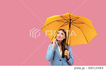 Portrait of angry young girl holding yellow umbrella Portrait of angry young girl holding yellow umbrella 68514464