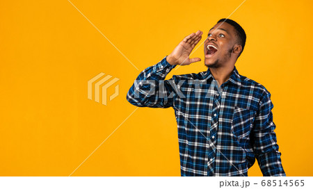 Positive Black Man Shouting Holding Hand Near Mouth, Yellow Background Positive Black Man Shouting Holding Hand Near Mouth, Yellow Background 68514565