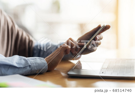 Female hands holding smartphone and using laptop 68514740