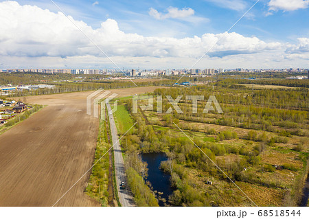 Spring field with road and city on background. Day 68518544
