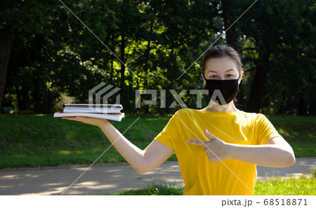 Beautiful female college student in black protective mask in a park outdoors  68518871